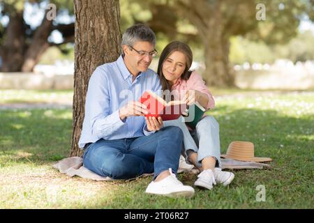 Reifes, romantisches Paar, das sich im Park entspannt und im Freien Bücher liest Stockfoto