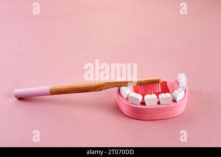 Nationaler Bürstentag. Zahn mit Zahnbürste auf rosa Hintergrund. Zahnärztliches Gesundheitskonzept. Stockfoto