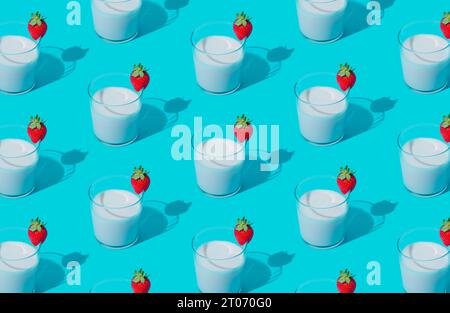 Kreative Musterkomposition aus Milchgetränk mit Erdbeergeschmack in Glasbecher auf hellblauem Hintergrund. Minimales Smoothie- oder Milchshake-Konzept. Stockfoto