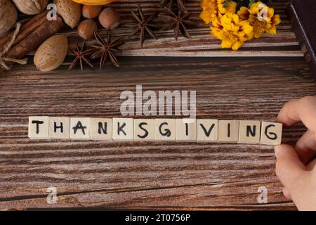 Thanksgiving Wort auf Holzwürfeln mit handgeschriebenen Buchstaben auf hölzernem Hintergrund mit Herbststillleben und Bibelbuch geschrieben. Tabellenansicht oben. Stockfoto