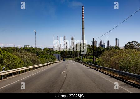 Straße mit den Türmen des Raffinerie-Kraftwerks Galp von Sines im Hintergrund. Sines in Portugal. Stockfoto