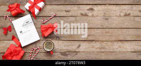 Papierkalender für Februar 2024 mit Geschenkboxen, Weihnachtsdekorationen und Tasse Kaffee auf hölzernem Hintergrund mit Platz für Text Stockfoto
