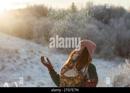 Porträt des glücklichen schönen Mädchens, der jungen freudigen positiven Frau, die mit Schnee, Schneeflocken, Spaß im Freien in Winterkleidung, Hut und Schal spielt, lächelnd. Wintersaison, Wetter. Hochwertige Fotos Stockfoto