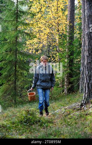 Eine junge Frau, die in einem Wald nach Pilzen sucht Stockfoto