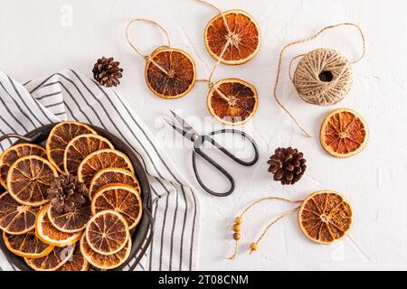 Getrocknete Orangenscheiben auf einem Vintage-Metalltablett, Schere, Garn für selbstgemachte Handarbeiten. Draufsicht. Flache Lagen Stockfoto