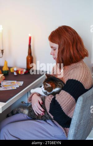 Mädchen, das eine Katze hält und Tarotkarten auslegt Stockfoto