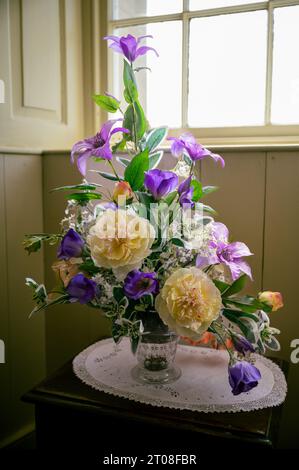 Wunderschöne bunte Blumen stehen auf einem alten Tisch drinnen im Skaill House Museum, Orkney Island, Schottland, vertikale Aufnahme Stockfoto