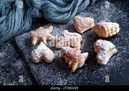 Hausgemachte Kekse mit Puderzucker auf schwarzem Hintergrund. Stockfoto