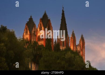 In der Lahn spiegelt sich das farbenfrohe Äußere der spätromanischen / frühgotischen Kathedrale St. Georg in Limburg an der Lahn, Hessen. Die Kathedrale mit sieben unterschiedlich hohen Türmen, darunter einer mit leicht geschwungenem Turm, wurde in den späten 1100er/frühen 1200er Jahren erbaut Das üppige und farbenfrohe Äußere verdankt es aufwändigen Restaurierungsarbeiten in den 1960er und 70er Jahren, deren Farben von Spuren der Originalfarbe bestimmt wurden. Stockfoto