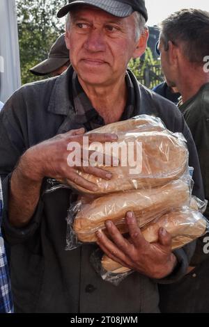 Orichhiv, Ukraine. Oktober 2023. Ein älterer Mann erhält Brotlaibe an einem Ort für humanitäre Hilfe in Orichhiv. Die ukrainischen Streitkräfte setzen ihre Gegenoffensive in der Nähe von Orichschiw in der Region Zaporischja fort. Quelle: SOPA Images Limited/Alamy Live News Stockfoto