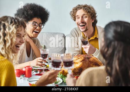 Glückliche multikulturelle Familienmitglieder, die an festlichem Tisch lachen und an Weingläsern klirren, Weihnachten Stockfoto