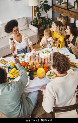 Fröhliche Freunde und Familie aus verschiedenen Volksgruppen, die während des Thanksgiving zu Abend essen Stockfoto