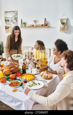 Happy Woman servierte Mahlzeit an Freunde und Familie zwischen Rassen während der Thanksgiving-Feier zu Hause Stockfoto