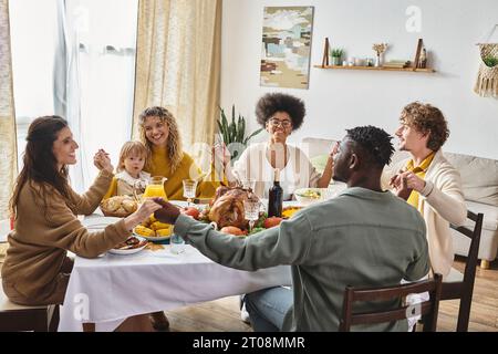 Glückliche multirassische Freunde und Familie, die Hände halten und am Thanksgiving-Tisch beten, dankbar Stockfoto