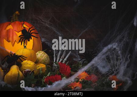 Halloween-Hintergrund mit Kürbissen, Kastanien, Blättern, Halloween-Dekorationen, Spinnen und Skeletthänden mit Spinnweben Stockfoto