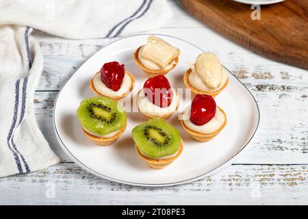Obsttörtchen. Erdbeer-, Bananen- und Kiwis-Tartlets auf einem Teller. Snack süße Speisen Stockfoto