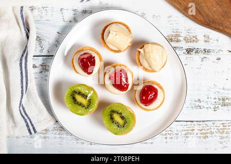 Obsttörtchen. Erdbeer-, Bananen- und Kiwis-Tartlets auf einem Teller. Snack süße Speisen. Draufsicht Stockfoto