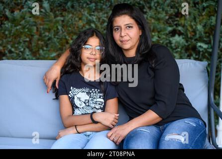 Berlin, Deutschland. September 2023. Sara sitzt mit ihrer Mutter Manizha Wodud auf einer Hollywoodschaukel in ihrem Garten. Der 12-jährige Gymnasium hat die häufigste Form der rheumatoiden Arthritis bei Kindern (juvenile ideopathische Arthritis). Die Diagnose ist besonders bei kleinen Kindern schwierig, da die Symptome stark variieren und sich von denen der Erwachsenen unterscheiden können. Bei Sara wurde im Alter von 11 Monaten Rheuma diagnostiziert. (Zu dpa 'Sehprobleme, steife Gelenke, oft müde: Tausende von Kindern haben Rheuma') Credit: Bernd von Jutrczenka/dpa/Alamy Live News Stockfoto