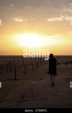 Eine Frau, die bei Sonnenuntergang zum Strand läuft Stockfoto