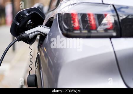 Dateifoto vom 03/21 eines Peugeot Elektroautos, das an eine EV-Ladestation angeschlossen wurde. Der Anteil der im letzten Monat zugelassenen Neuwagen, die batteriebetrieben waren, war niedriger als ein Jahr zuvor, wie neue Zahlen zeigen. Nur 16,6 % der Zulassungen im September waren rein elektrisch, verglichen mit 16,9 % im selben Monat im Jahr 2022, sagte die Gesellschaft der Automobilhersteller und -Händler. Ausgabedatum: Donnerstag, 5. Oktober 2023. Stockfoto