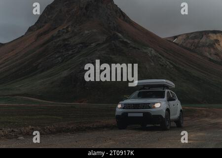 Dacia Duster 4x4 mit einem Dachzelt im Gelände in Landmannalaugar in Island. Seitenaufnahme mit Lichtern und Kies im Vordergrund. Wir sehen Co Stockfoto