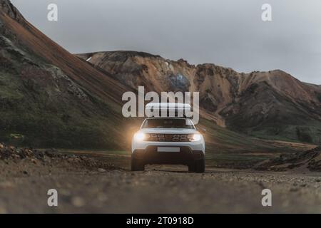 Dacia Duster 4x4 mit einem Dachzelt im Gelände in Landmannalaugar in Island. Frontaufnahme mit Lichtern und Schotter im Vordergrund. Wir sehen c Stockfoto