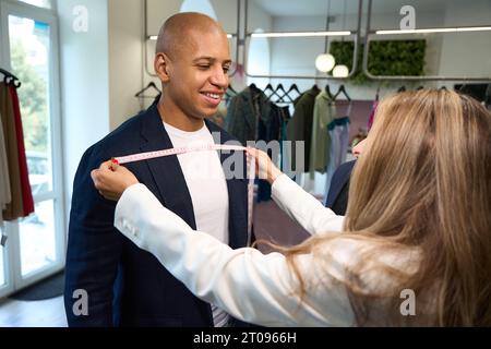 Erfahrene Schneiderin, die Körpermessungen des Kunden durchführt Stockfoto