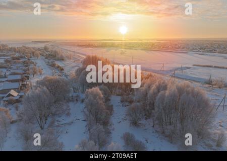 Frost in Bäumen bei Sonnenaufgang geht die Sonne über Felder im Schnee auf. Luftaufnahme Stockfoto