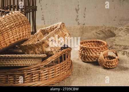 Eine Gruppe von Körben verschiedener Formen, die aus natürlichen Materialien auf einer Sackleinen-Tischdecke gewebt werden. Stockfoto