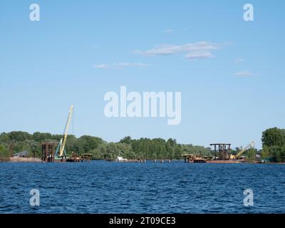Bau einer Brücke über den Fluss zur Insel im Bau. Kran auf der Baustelle Stockfoto