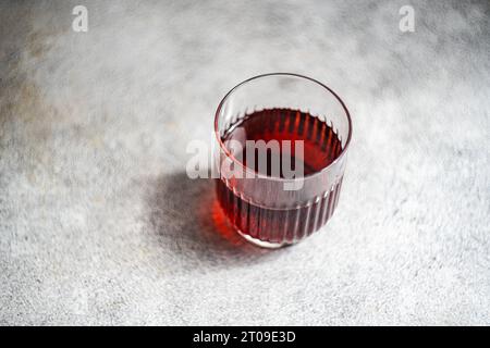 Hoher Winkel des traditionellen georgianischen Saperavi-Rotweins in transparentem Glas serviert auf einem sauberen Betontisch mit grauem Hintergrund Stockfoto