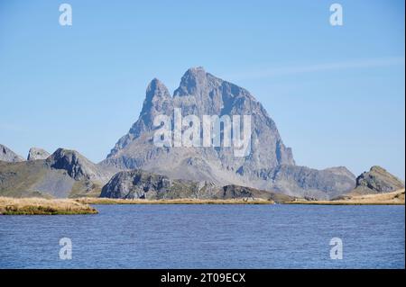 Malerischer Blick auf den ruhigen See, umgeben von Pic du Midi d'Ossau Bergkette vor wolkenlosem blauem Himmel in den französischen Pyrenäen Stockfoto