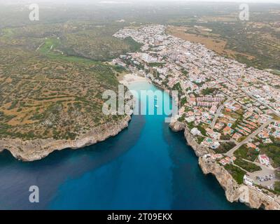 Von oben aus blickt man auf die türkisfarbene Lagune auf Menorca Island mit Resorthäusern und Grün Stockfoto