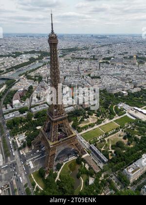 Von oben aus haben Sie einen malerischen Blick auf den berühmten Eiffelturm, der sich auf einem grünen Hügel vor bewölktem Himmel in Paris befindet Stockfoto