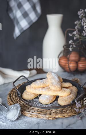 Tablett mit knusprigem Ladyfingers Finger Biskuit auf Tisch neben Eiern und Glas auf grauem Hintergrund in der Küche zu Hause Stockfoto