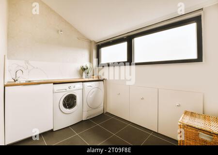 Innenraum des Waschraums mit weißer Waschmaschine am Fenster in einem modernen Apartment Stockfoto