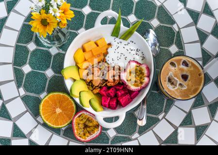 Müsli mit griechischem Joghurt, Honig, frischem Obst, Chiasamen, serviert mit Ice americano Stockfoto