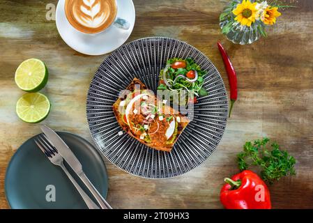 Zerstoßene Avocado mit pochierten Eiern, Pesto mit rotem Pfeffer und Gurkenschalotte auf Toast von oben Stockfoto
