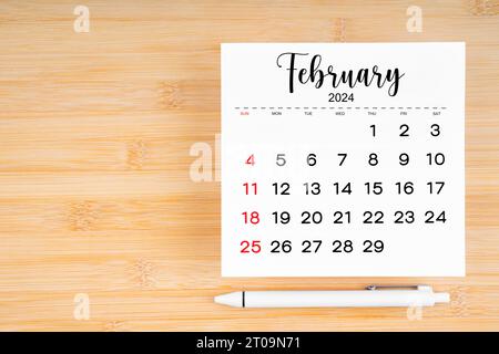 Februar 2024 Kalenderseite und Stift auf hölzernem Hintergrund mit leerem Platz. Stockfoto