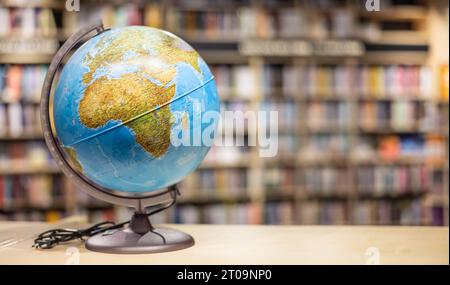 Ein Globus als Schulausrüstung, die in einem Regal in der Schulbibliothek platziert wurde. Leerzeichen für Text. Stockfoto