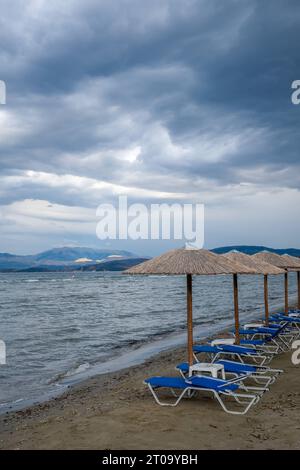 Kalamaki, Korfu, Griechenland - Sonnenliegen und Sonnenschirme am Kalamaki Strand im Nordosten der griechischen Insel Korfu. Hinterland Albanien. Kalamaki Korfu Griechenland *** Kalamaki, Korfu, Griechenland Liegen und Sonnenschirme am Kalamaki Strand im Nordosten der griechischen Insel Korfu zurück Festland Albanien Kalamaki Korfu Griechenland Stockfoto