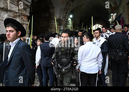 Altstadt Jerusalem, Israel. Oktober 2023. Eine israelische Grenzpolizei durchquert orthodoxe Juden, betend in der Nähe eines Eingangs zum Tempelberg, oder Al Aqsa Compound, im muslimischen Viertel der Altstadt von Jerusalem, während des jüdischen Festes von Sukkot, dem Tabernakelfest, am Donnerstag, den 5. Oktober 2023. Foto: Debbie Hill/ Credit: UPI/Alamy Live News Stockfoto