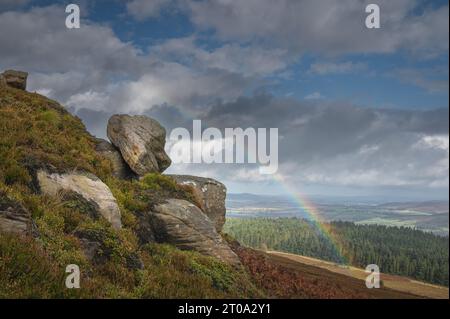 Regenbogen über Simonside Hills und Felsen. Blick auf die Cheviots. Northumberland. Stockfoto