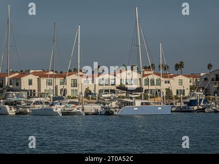 Ventura, CA, USA - 14. September 2023: Loungegebäude mit beigefarbener Fassade und rotem Dach zum Hafen hin, wo sich mehrere Yachten, Segel und Motor befinden Stockfoto