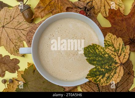 Tasse Kaffee mit Ahornblatt auf Herbsthintergrund, Draufsicht. Hochwertige Fotos Stockfoto