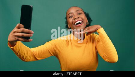 Glückliche junge Frau macht Selfies, grünes Studio-Porträt Stockfoto