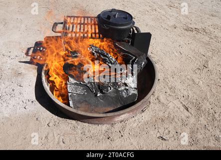Genießen Sie die freie Natur mit Lagerfeuer-Kochkunst – ein niederländischer Ofen, der über den Flammen kocht – die Essenz des Camping-Glücks. Stockfoto