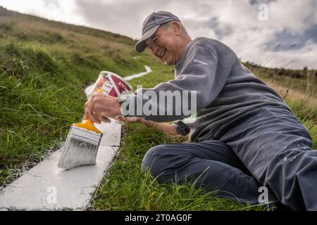 Volunters malen die Betonsteine, aus denen der lange Mann von Wilmington in East Sussex besteht. Ursprünglich wurde er in die Kreide des South Down gehauen. Stockfoto