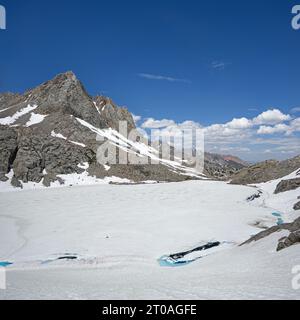 Picture Peak und ein meist gefrorener Echo Lake in der John Muir Wilderness der Sierra Nevada Mountains im Juli eines Hochschneejahres Stockfoto