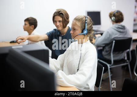 Junge helfen verärgert Mädchen, um Problem auf dem Computer in der Schulklasse zu lösen Stockfoto